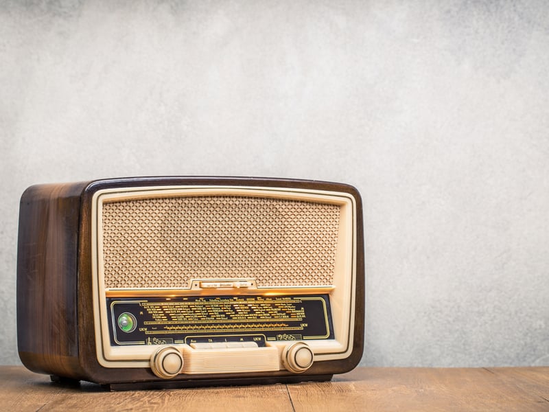 A photograph of a retro looking radio against a grey background.