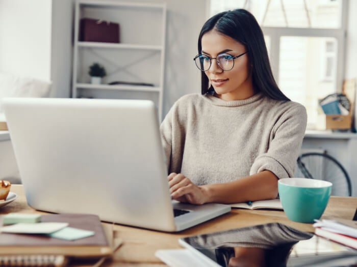 A woman looks eagerly into a laptop in a busy home office space